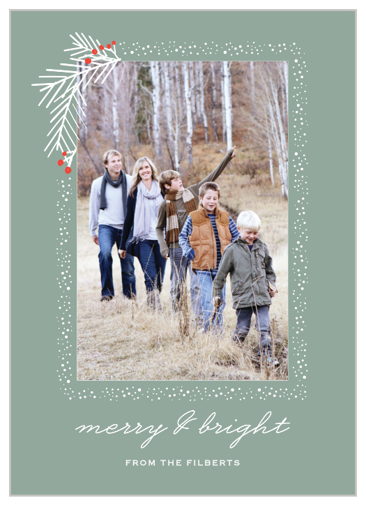 Snow frames your family portrait with a holly flourish on the top left corner of the Pine Branches Photo Holiday Cards. 
